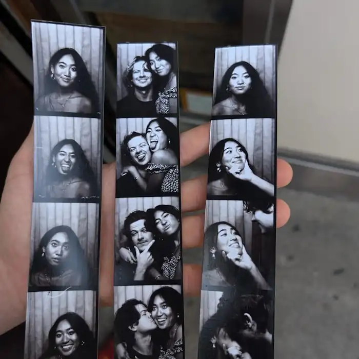 Black and white photo booth strips held up after a party